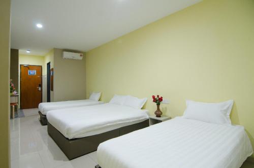 two beds in a hotel room with white sheets at Hotel Raja Bot in Kuala Lumpur