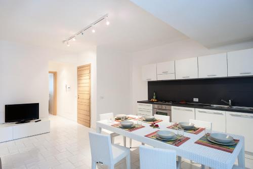 a white kitchen with a white table and chairs at NerOssidiana in Acquacalda