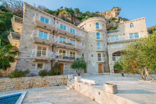 un gran edificio de piedra con árboles delante de él en Pietra Mare Apartments, en Petrovac na Moru