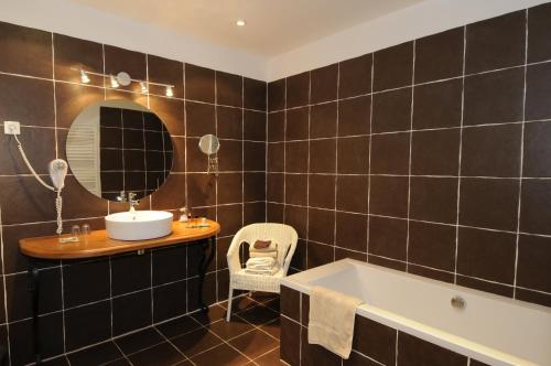 ein Badezimmer mit einer Badewanne, einem Waschbecken und einem Spiegel in der Unterkunft Maison de la Pra in Valence