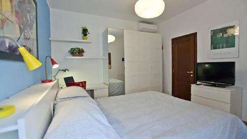 1 dormitorio con 1 cama blanca y TV en Colosseo Luxury Apartment, en Roma