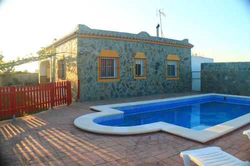 een huis met een zwembad naast een gebouw bij Chalet Aroca in Conil de la Frontera