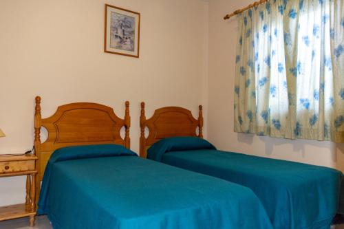 La Playa CaleraにあるApartamento Casanova 1Aのベッドルーム1室(青いシーツが備わるベッド2台付)