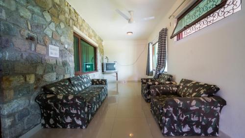 a waiting room with couches and a stone wall at Hideaway By Aahma in Rāmnagar