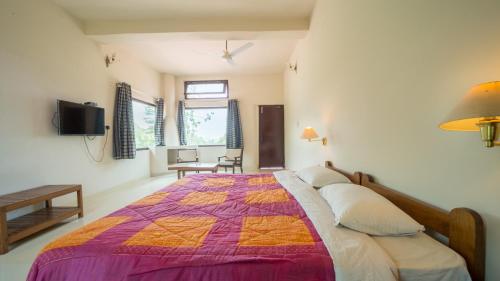 a bedroom with a bed with a purple and orange quilt at Hideaway By Aahma in Rāmnagar