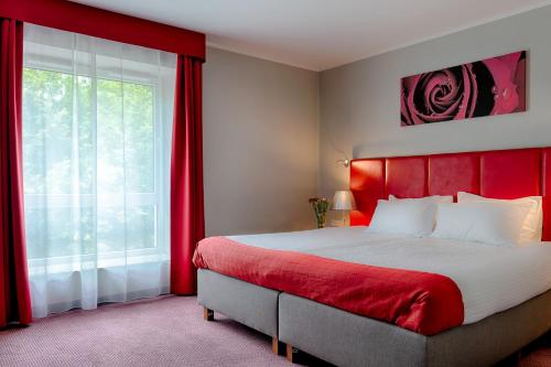 a bedroom with a bed with a red headboard and a window at Focus Hotel Katowice Chorzów in Chorzów