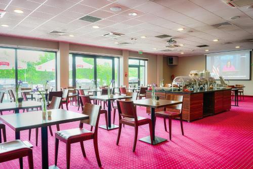 a restaurant with tables and chairs and a screen at Focus Hotel Katowice Chorzów in Chorzów