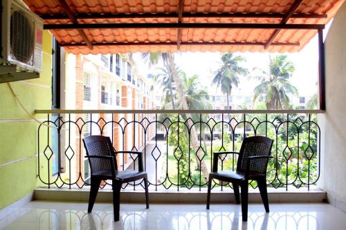 Dos sillas sentadas frente a un balcón con ventana. en Comfy 2BHK Pool facing Full Aircon Apt in Candolim, en Candolim