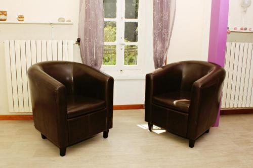 two brown leather chairs in a room with a window at Auberge Le Romarin in Valgorge