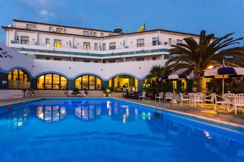 a hotel with a swimming pool at night at Hotel Poseidon in Diamante