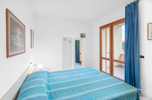 a white bedroom with a bed with blue sheets at Cassiopea in Marina di Campo