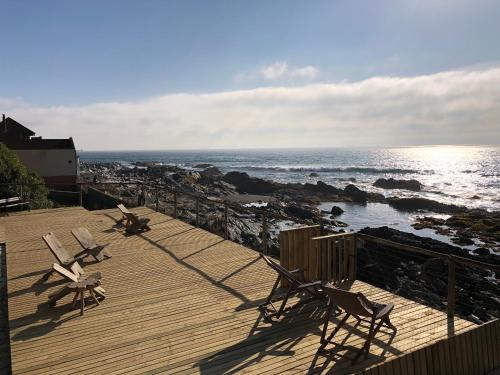 two chairs on a wooden deck overlooking the ocean at Delfín Apart in Pichilemu