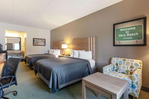 una habitación de hotel con 2 camas y una silla en Econo Lodge Vero Beach - Downtown, en Vero Beach