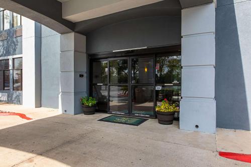 an entrance to a building with potted plants in front at Quality Suites Austin South Street Elmo District in Austin