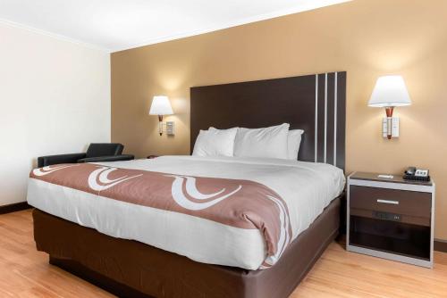 a hotel room with a large bed and a chair at Quality Inn in Fairborn