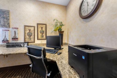 a desk with a computer and a clock on the wall at Comfort Suites in Findlay