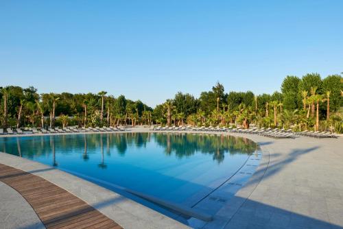 une grande piscine avec des chaises et des arbres dans l'établissement BJ Riviera, à Grimaud
