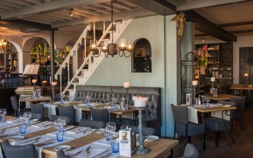 a dining room with tables and chairs and a staircase at l'Auberge Damhotel in Edam