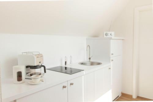 een witte keuken met een koffiezetapparaat op een aanrecht bij Boardinghouse s' Johanner in Saarbrücken