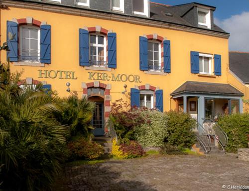 a yellow building with blue windows and a hotel trapdoor at Hôtel Kermor in Concarneau