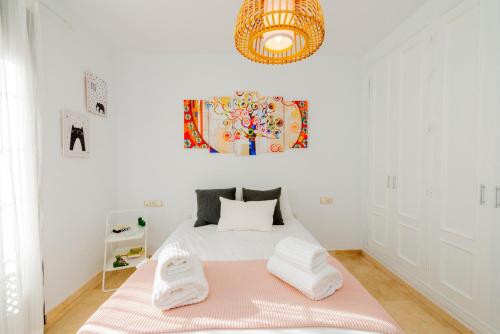 een witte slaapkamer met een bed met een roze deken bij Apartamento Turístico La Vega in Antequera