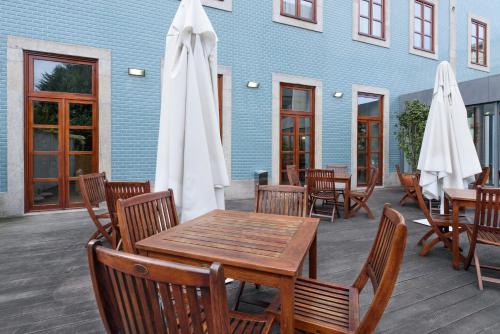 a patio with tables and chairs and white umbrellas at Eurostars das Artes in Porto