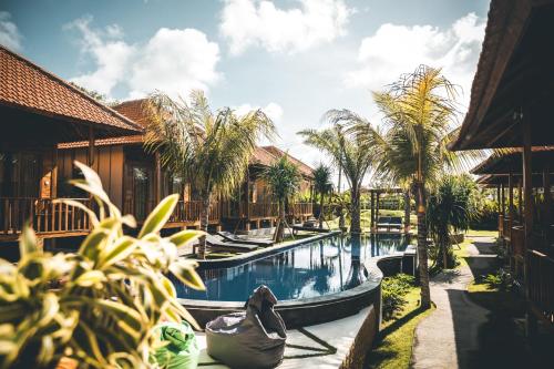 a pool at a resort with palm trees at Ocho Bali Surf Camp in Uluwatu