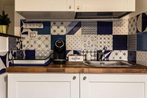 un bancone della cucina con lavandino e piastrelle bianche e blu di La casa di Alice a Salerno
