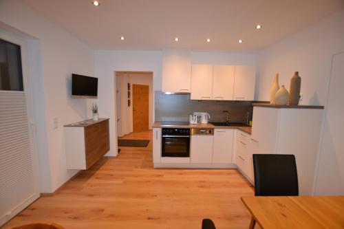 a kitchen with white cabinets and a wooden floor at fewo kramer in Heiterwang