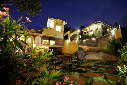 a table and chairs in front of a house at night at Vista Del Lago in Ambalavayal