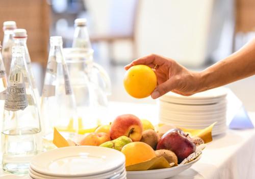 a person holding an orange over a bowl of fruit at TH Lazise - Hotel Parchi Del Garda in Lazise
