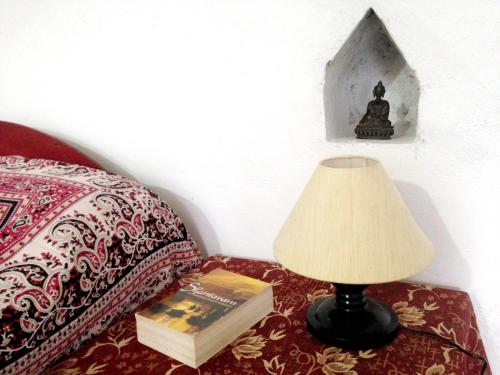 una lámpara y un libro sobre una mesa junto a una cama en Friends in Khajuraho en Khajurāho