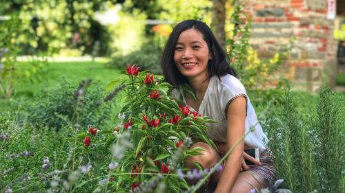 a woman sitting in the grass next to some flowers at Agriturismo Casa Agricola Rossi Appartamenti in Casentino in Soci