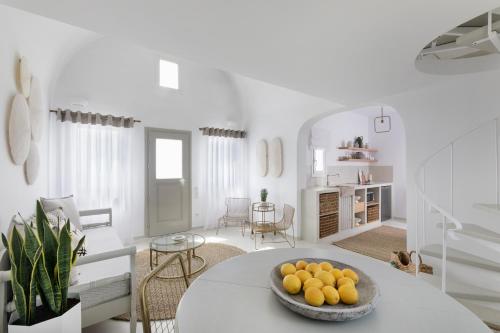 a white living room with a bowl of oranges on a table at The 360° Caldera view house by Caldera Houses in Imerovigli