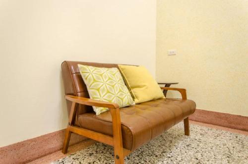 a brown leather chair with two yellow pillows on it at Freedom B&B in Tainan