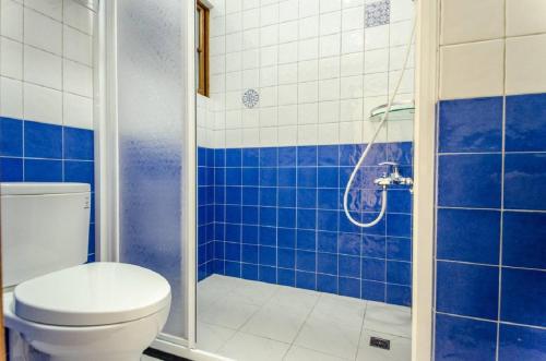 a blue tiled bathroom with a toilet and a shower at Freedom B&B in Tainan