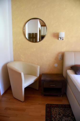 a bedroom with a white chair and a mirror at Frühstückspension Pachler in Gosau