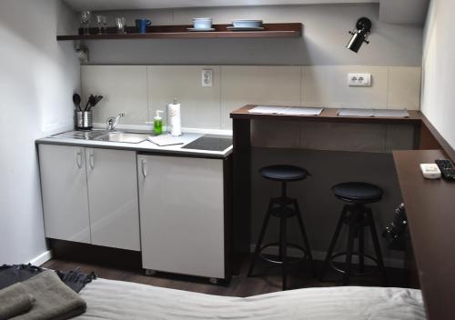 a kitchen with a sink and two bar stools at Apartmani Zrenjanin in Zrenjanin