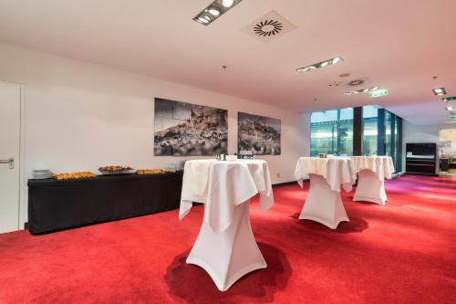a row of tables in a room with red carpet at Exe Budapest Center in Budapest