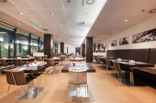 a restaurant with wooden tables and chairs and windows at Exe Budapest Center in Budapest