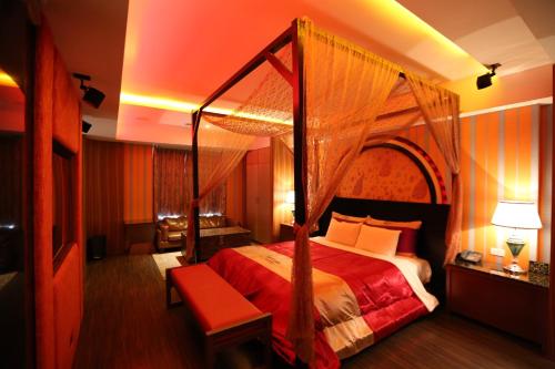 a bedroom with a canopy bed with a red blanket at Yosemite Motel - Taiyuan Branch in Taichung