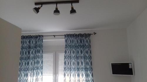 a room with a window with blue curtains and a television at HILLS Apartments in Vršac