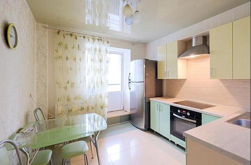 トムスクにあるДвухкомнатные апартаменты Советская 69のキッチン(ガラステーブル、冷蔵庫付)