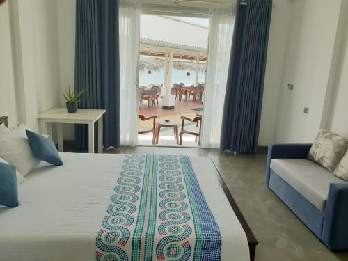 a bedroom with a bed and a couch and a table at Hotel Blue Note in Hikkaduwa