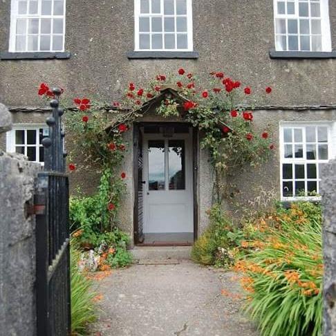 a house with a door with red roses on it at Witherslack Hall Farmhouse in Grange Over Sands