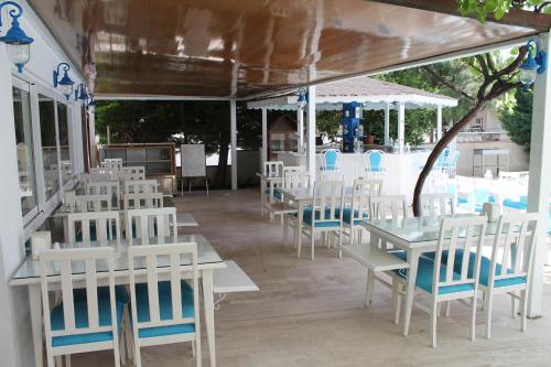 チェシメにあるAltinyaz Hotelの白いテーブルと椅子、プール付きのレストラン