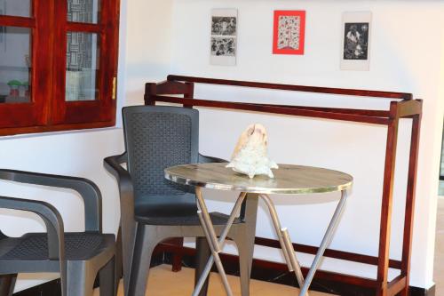 a table with a shell on top of it next to two chairs at Relax Beach House in Tangalle