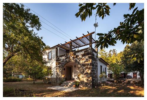 a stone house with an archway in the yard at Quinta da Regadas in Arouca