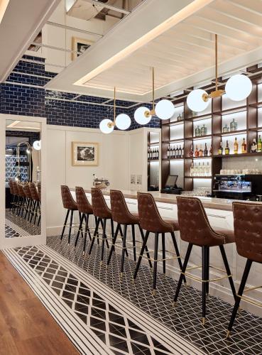 a dining room with a bar with brown chairs at Radisson Blu 1882 Hotel, Barcelona Sagrada Familia in Barcelona