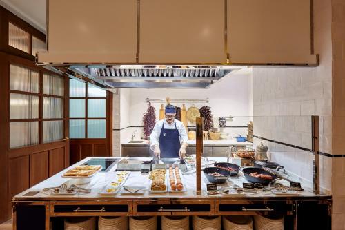 a kitchen with a chef preparing food on a counter at Radisson Blu 1882 Hotel, Barcelona Sagrada Familia in Barcelona